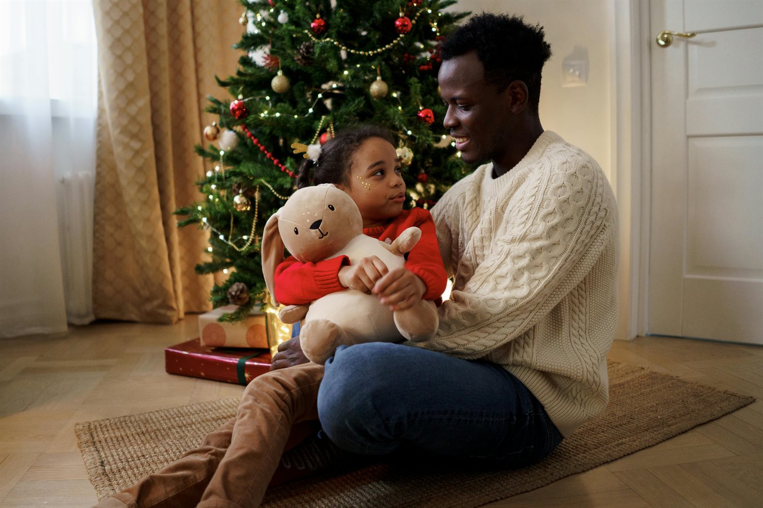 Image of father and daughter around the Christmas tree.